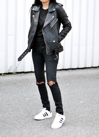 Look alla moda per donna: Giacca da moto in pelle nera, T-shirt girocollo nera, Jeans aderenti strappati neri, Sneakers basse in pelle bianche e nere