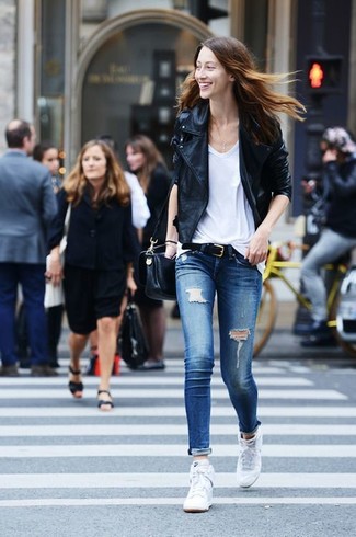 Look alla moda per donna: Giacca da moto in pelle nera, T-shirt con scollo a v bianca, Jeans aderenti strappati blu, Sneakers alte bianche