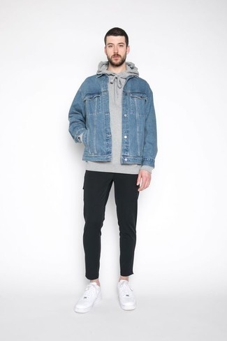Look alla moda per uomo: Giacca di jeans azzurra, Felpa con cappuccio grigia, Chino neri, Sneakers basse in pelle bianche