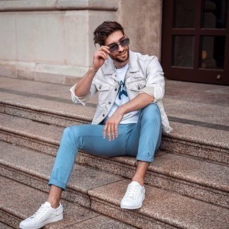 Look alla moda per uomo: Giacca di jeans bianca, T-shirt girocollo stampata bianca e blu scuro, Chino azzurri, Sneakers basse di tela bianche
