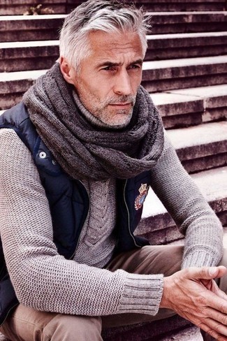 Come indossare e abbinare un maglione grigio per un uomo di 50 anni in autunno 2024: Mostra il tuo stile in un maglione grigio con chino beige per affrontare con facilità la tua giornata. Una buona idea per essere elegante in questa stagione autunnale!