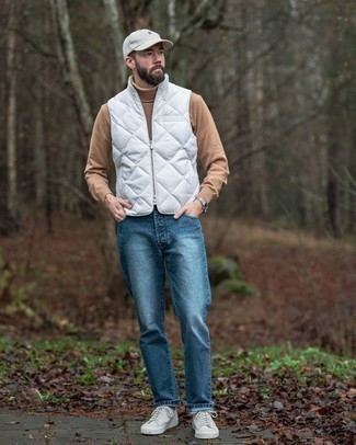 Look alla moda per uomo: Gilet trapuntato bianco, Dolcevita di lana marrone chiaro, Jeans blu, Sneakers basse di tela bianche
