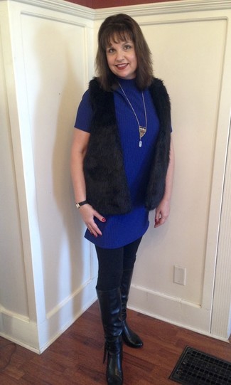 Look alla moda per donna: Gilet di pelliccia nero, Vestito di maglia blu, Stivali al ginocchio in pelle neri, Collana dorata