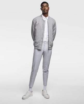 Look alla moda per uomo: Giubbotto bomber grigio, Camicia elegante bianca, Chino a righe verticali grigi, Sneakers basse in pelle bianche e nere
