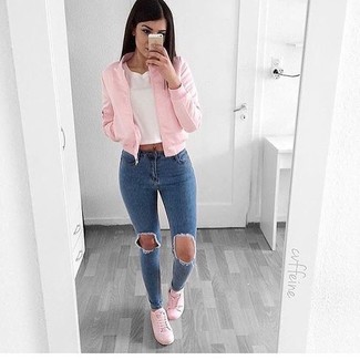 Moda donna anni 20 in modo rilassato: Opta per il comfort in un giubbotto bomber rosa e jeans aderenti strappati blu. Questo outfit si abbina perfettamente a un paio di sneakers basse rosa.