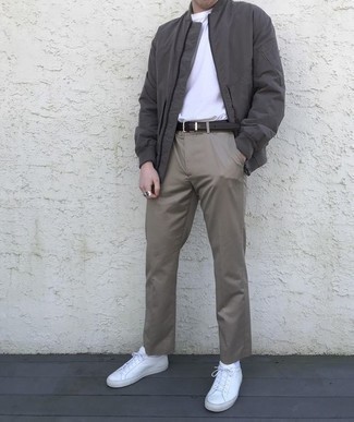 Look alla moda per uomo: Giubbotto bomber grigio scuro, T-shirt girocollo bianca, Chino grigi, Sneakers basse di tela bianche