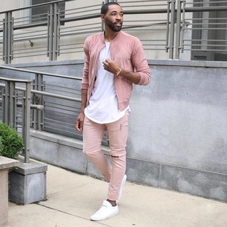 Come indossare e abbinare jeans fucsia per un uomo di 30 anni: Mostra il tuo stile in un giubbotto bomber rosa con jeans fucsia per un look spensierato e alla moda. Questo outfit si abbina perfettamente a un paio di sneakers basse bianche.