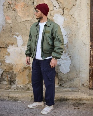 Look alla moda per uomo: Giubbotto bomber verde oliva, T-shirt girocollo bianca, Pantaloni cargo blu scuro, Sneakers alte di tela bianche