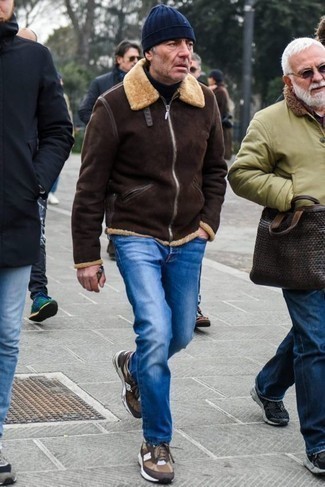Quale giubbotto in shearling indossare con jeans blu per un uomo di 50 anni in inverno 2025: Opta per un giubbotto in shearling e jeans blu per vestirti casual. Scarpe sportive marroni danno un tocco informale al tuo abbigliamento. È eccellente idea per un outfit invernale!