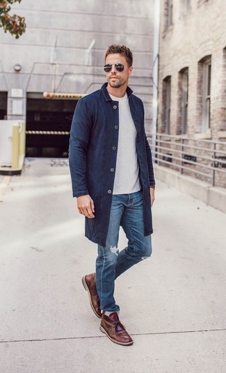 Quale jeans indossare con chukka marroni in primavera 2025 in modo rilassato: Scegli un outfit composto da un impermeabile blu scuro e jeans per una sensazione di semplicità e spensieratezza. Sfodera il gusto per le calzature di lusso e calza un paio di chukka marroni. Un outfit magnifico per essere elegante e alla moda anche durante la stagione primaverile.