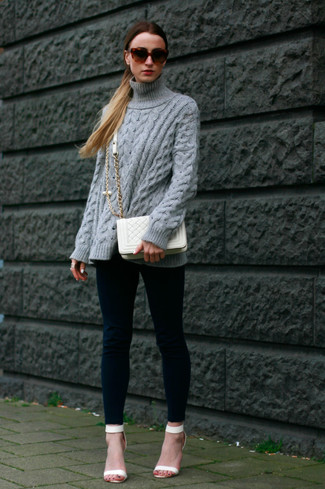 Come indossare e abbinare un maglione a trecce per una donna di 30 anni: Indossa un maglione a trecce con leggings blu scuro per un look comfy-casual. Sandali con tacco bianchi sono una valida scelta per completare il look.