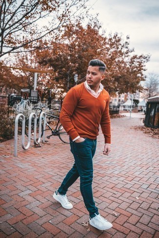 Come indossare e abbinare un maglione con scollo a v arancione in modo casual: Indossa un maglione con scollo a v arancione e jeans blu scuro per un fantastico look da sfoggiare nel weekend. Sneakers basse in pelle bianche e blu scuro sono una eccellente scelta per completare il look.