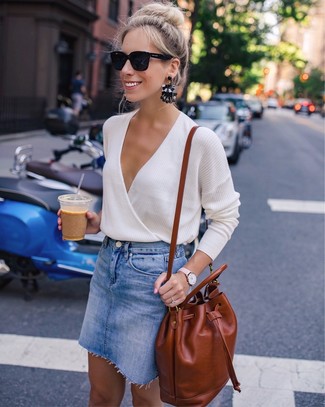 Look alla moda per donna: Maglione con scollo a v beige, Minigonna di jeans blu, Zaino in pelle terracotta, Occhiali da sole neri