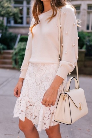 Come indossare e abbinare una borsa bianca in modo casual: Indossa un maglione girocollo decorato rosa e una borsa bianca per un look trendy e alla mano.