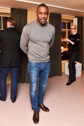 Look di Idris Elba: Maglione girocollo grigio, Jeans blu, Scarpe brogue in pelle marrone scuro
