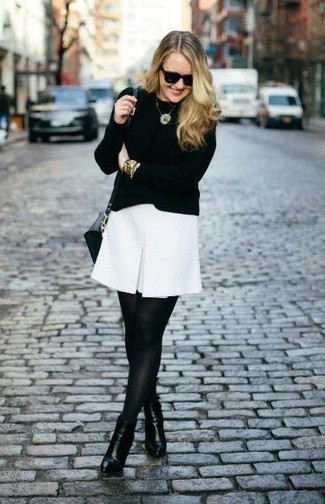Look alla moda per donna: Maglione girocollo nero, Vestito a trapezio bianco, Stivaletti in pelle neri, Borsa a tracolla in pelle nera