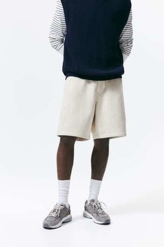 Look alla moda per uomo: Maglione senza maniche blu scuro, T-shirt manica lunga a righe orizzontali bianca e blu scuro, Pantaloncini sportivi beige, Scarpe sportive grigie