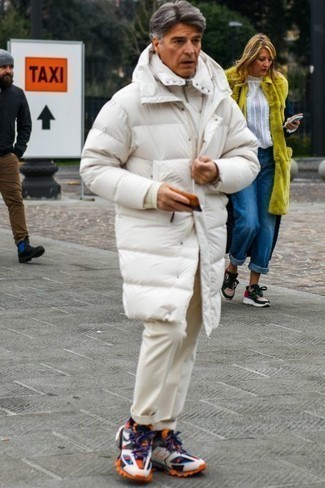 Trend da uomo 2023: Abbina un piumino lungo bianco con chino beige per un look semplice, da indossare ogni giorno. Non vuoi calcare troppo la mano con le scarpe? Opta per un paio di scarpe sportive multicolori per la giornata.