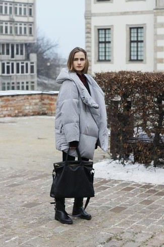 Look alla moda per donna: Piumino lungo grigio, Maglione oversize nero, Jeans aderenti neri, Stivali al polpaccio in pelle neri
