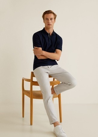 Look alla moda per uomo: Polo blu scuro, Chino grigi, Sneakers basse di tela bianche