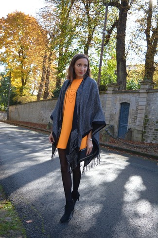 Look alla moda per donna: Poncho grigio, Vestito a trapezio arancione, Stivaletti in pelle scamosciata neri, Pochette in pelle nera
