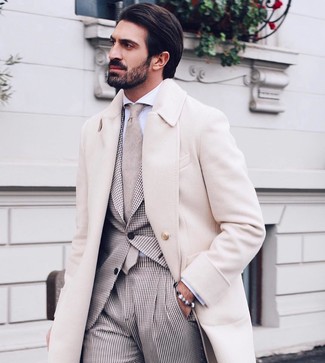 Come indossare e abbinare un abito beige per un uomo di 30 anni quando fa gelo: Combina un abito beige con un soprabito beige come un vero gentiluomo.