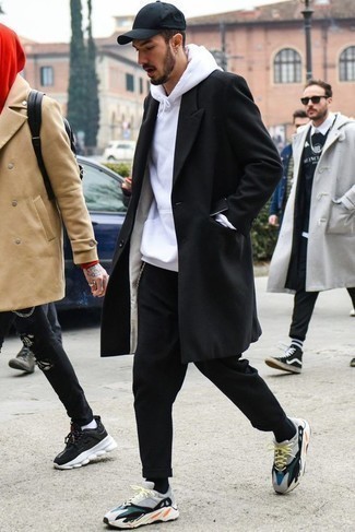 Look alla moda per uomo: Soprabito nero, Felpa con cappuccio bianca, Chino neri, Scarpe sportive multicolori