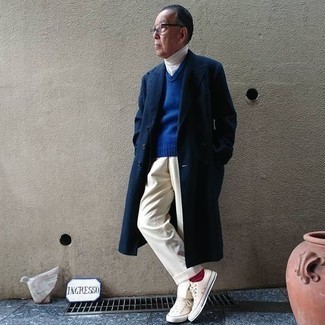 Moda uomo anni 60: Indossa un soprabito blu scuro e pantaloni eleganti beige come un vero gentiluomo. Non vuoi calcare troppo la mano con le scarpe? Indossa un paio di sneakers basse di tela beige per la giornata.