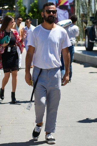 Look alla moda per uomo: T-shirt girocollo bianca, Chino grigi, Sneakers basse di tela nere e bianche, Occhiali da sole marrone scuro
