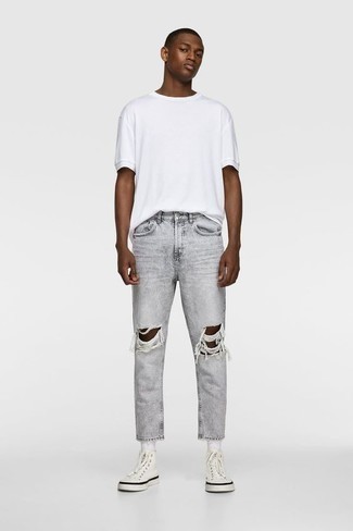 Quale jeans indossare con una t-shirt girocollo bianca in modo rilassato: Metti una t-shirt girocollo bianca e jeans per una sensazione di semplicità e spensieratezza. Se non vuoi essere troppo formale, scegli un paio di sneakers alte di tela bianche come calzature.