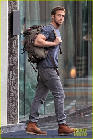 Look di Ryan Gosling: T-shirt girocollo blu scuro, Jeans grigi, Stivali da lavoro in pelle marroni, Zaino di tela verde oliva