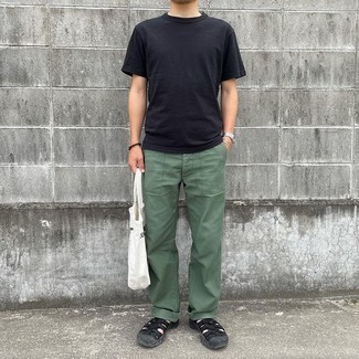 Look alla moda per uomo: T-shirt girocollo nera, Chino verde scuro, Sandali di tela neri, Borsa shopping di tela stampata bianca e nera