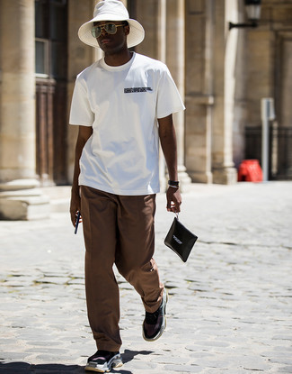 Look alla moda per uomo: T-shirt girocollo stampata bianca e nera, Chino marroni, Scarpe sportive nere, Pochette in pelle stampata nera e bianca