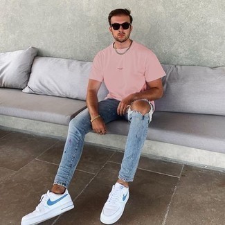 Look alla moda per uomo: T-shirt girocollo rosa, Jeans aderenti strappati azzurri, Sneakers basse di tela bianche e blu, Occhiali da sole marrone scuro