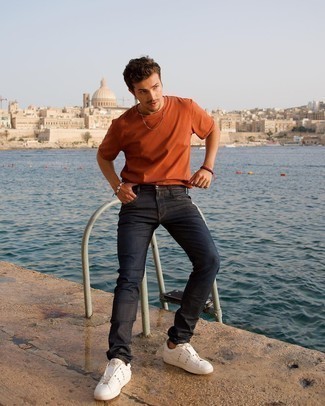 Moda uomo anni 30 quando fa molto caldo in modo casual: Potresti indossare una t-shirt girocollo arancione e jeans blu scuro per vestirti casual. Sneakers basse in pelle con borchie bianche sono una gradevolissima scelta per completare il look.