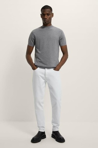 Come indossare e abbinare jeans bianchi: Per un outfit della massima comodità, combina una t-shirt girocollo lavorata a maglia grigia con jeans bianchi. Prova con un paio di stivali chelsea in pelle neri per un tocco virile.