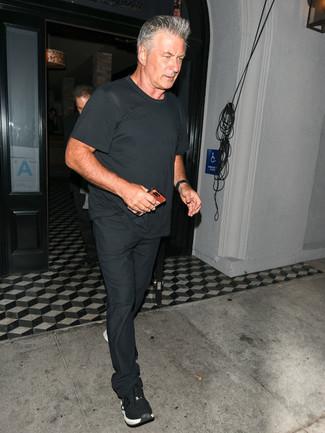 Moda uomo anni 60 in modo casual: Abbina una t-shirt girocollo nera con chino neri per un look trendy e alla mano. Calza un paio di scarpe sportive nere per un tocco più rilassato.