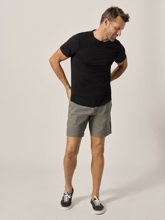 Moda uomo anni 40 quando fa molto caldo: Abbina una t-shirt girocollo nera con pantaloncini grigi per un look spensierato e alla moda. Sneakers basse di tela nere e bianche sono una valida scelta per completare il look.