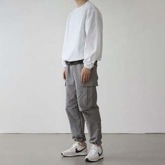 Look alla moda per uomo: T-shirt girocollo nera, T-shirt manica lunga bianca, Pantaloni cargo grigi, Scarpe sportive bianche e nere