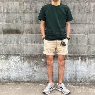 Trend da uomo 2021: Combina una t-shirt girocollo verde scuro con pantaloncini beige per un outfit comodo ma studiato con cura. Scegli un paio di scarpe sportive grigie come calzature per un tocco più rilassato.