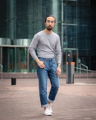 Look alla moda per uomo: T-shirt manica lunga grigia, Jeans blu, Sneakers basse di tela bianche, Occhiali da sole trasparenti