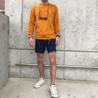 Trend da uomo 2021: Punta su una t-shirt manica lunga arancione e pantaloncini di jeans blu scuro per un look spensierato e alla moda. Sneakers basse di tela bianche sono una interessante scelta per completare il look.