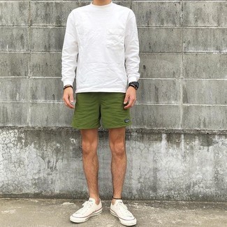 Moda uomo anni 30: Scegli un outfit rilassato in una t-shirt manica lunga bianca e pantaloncini sportivi verde oliva. Scegli un paio di sneakers basse di tela bianche come calzature per dare un tocco classico al completo.