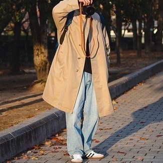 Look alla moda per uomo: Trench marrone chiaro, T-shirt manica lunga marrone scuro, Jeans azzurri, Sneakers basse di tela bianche e nere