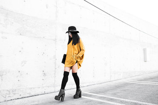 Come indossare e abbinare un borsalino quando fa caldo in modo smart-casual: Indossa un vestito di maglia senape con un borsalino per un'atmosfera casual-cool. Stivaletti in pelle pesanti neri sono una buona scelta per completare il look.